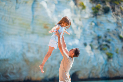 Side view of father holding daughter midair