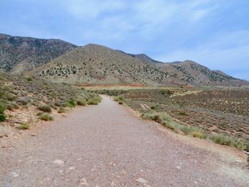 Road leading towards mountains against sky