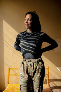 Portrait of young ukrainian woman in military clothes standing against wall