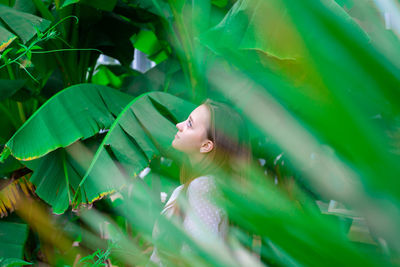 Close-up of young woman standing by banana leaf outdoors