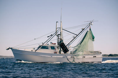 Shrimpboat sailing on sea against clear sky