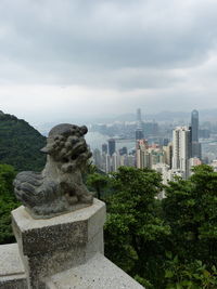 Statue in city against cloudy sky