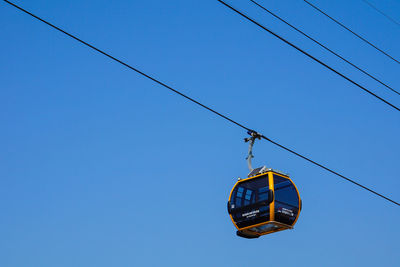 Low angle view of overhead cable car against clear blue sky