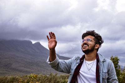 Young man standing by mountain against sky