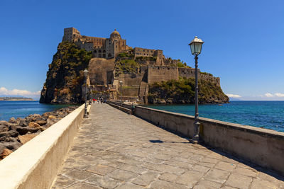 View of fort by sea against blue sky