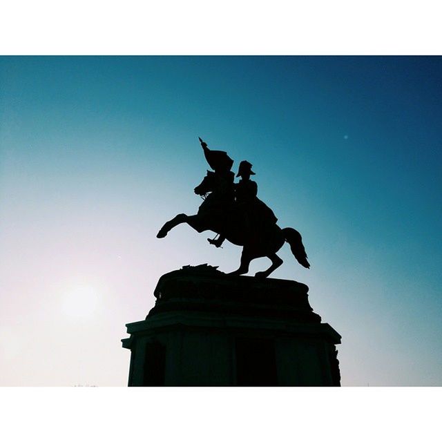 statue, transfer print, low angle view, sculpture, human representation, auto post production filter, art and craft, clear sky, art, architecture, built structure, building exterior, creativity, copy space, silhouette, sky, blue, history