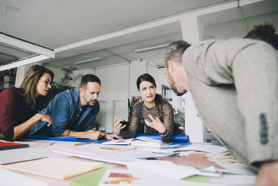 Confident businesswoman explaining colleagues during meeting in creative office