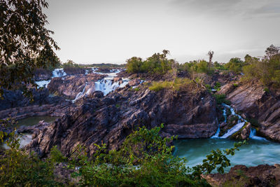 Scenic view of rocks by river against sky