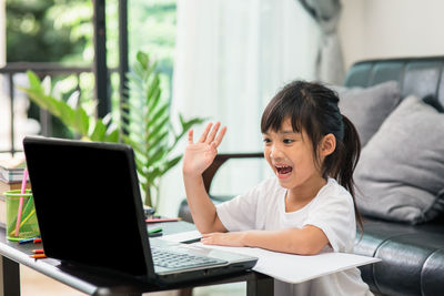 Portrait of girl sitting on table at home