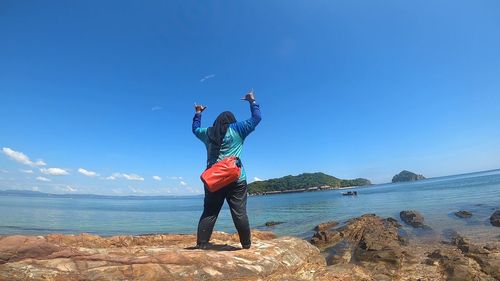 Full length of man standing at beach against blue sky