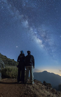Men standing on field against sky at night