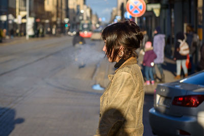 Rear view of woman standing on road in city