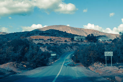 Road leading towards mountains against sky