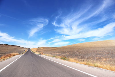 Road amidst field against sky