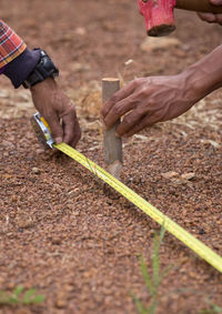 Cropped hands of people using tape measure at construction site