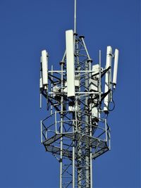 Low angle view of communications tower against clear blue sky