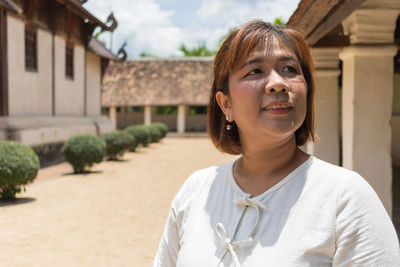 Close-up of smiling woman looking away while standing by temple