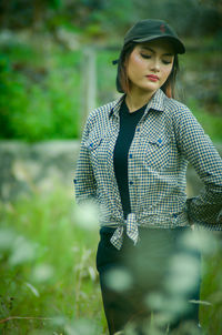 Young woman standing against plants