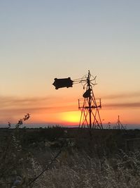 Silhouette cranes against sky during sunset