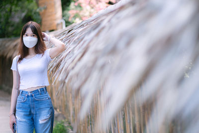 Young woman standing against plants