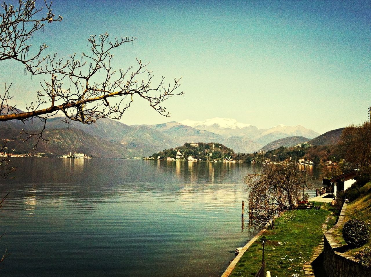 mountain, water, lake, mountain range, tranquil scene, scenics, tree, tranquility, beauty in nature, clear sky, nature, bare tree, sky, reflection, landscape, river, idyllic, building exterior, countryside, blue