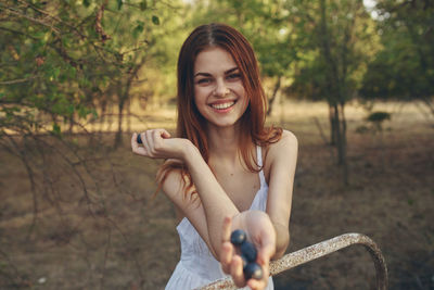 Portrait of smiling young woman holding grape