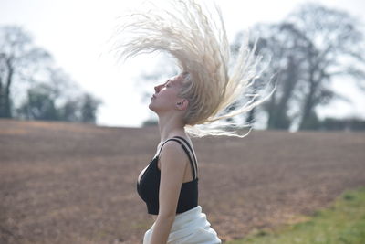 Young woman tossing hair while standing outdoors