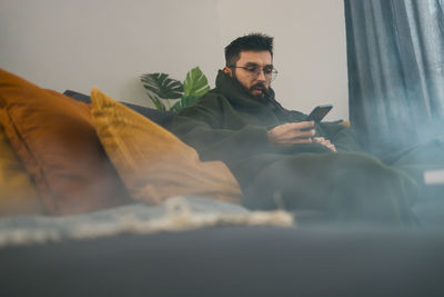 Young man sitting on bed at home