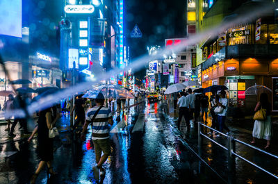 Crowd on city street during rainfall at night