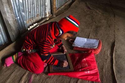 High angle view of boy writing on slate at home