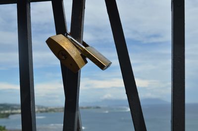 Close-up of padlocks on bridge against sky