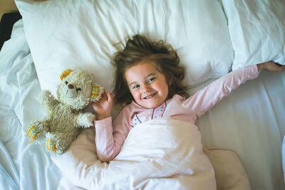 Girl lying on bed with stuffed toy at home