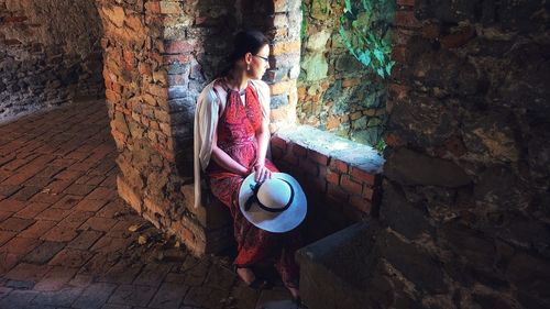 Full length of woman sitting on wall