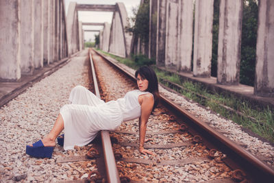 Side view of woman sitting on railroad track