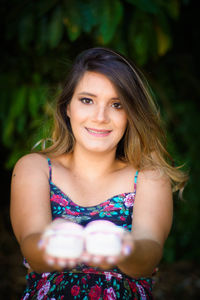 Portrait of young woman holding baby booties