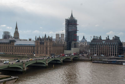 View of bridge over river in city against cloudy sky