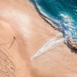 Aerial view of woman walking on sand at beach