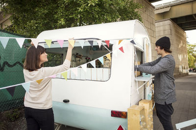 Male and female owners working outside food truck on street