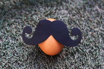 High angle view of artificial mustache on brown egg