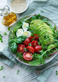 Fresh summer salad with arugula, red cherry tomatoes, basil, eggs and avocado. vegan food. 