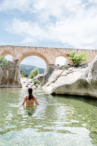 Rear view of woman walking through a majestic and clear waters river in teruel, spain. 