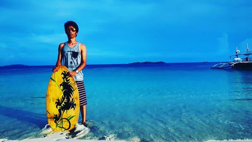 Young man standing with skimboard on shore at calaguas island