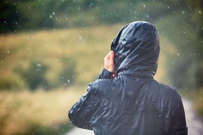 Rear view of man wearing raincoat on rainy day