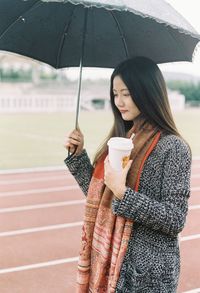 Young woman holding umbrella standing outdoors