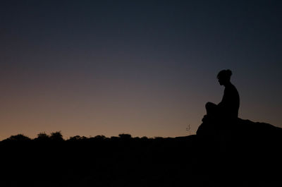 Silhouette people sitting against clear sky during sunset