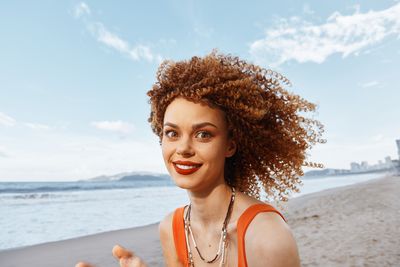 Portrait of young woman against sky