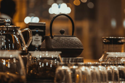 Close-up of kettle with drinking glasses on table