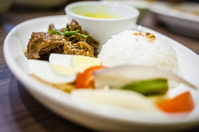 Close-up of meat with rice and vegetable served on table