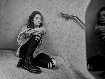 Portrait of woman sitting against wall