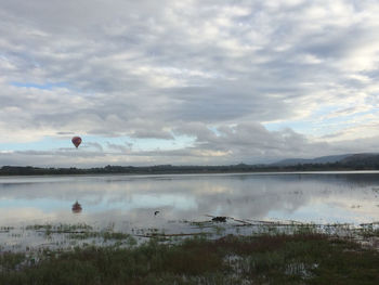 Scenic view of lake against cloudy sky